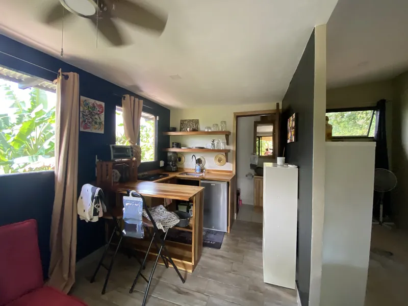 The kitchenette with a butcher-block bar, folding stools, floating shelves, and a navy accent wall.