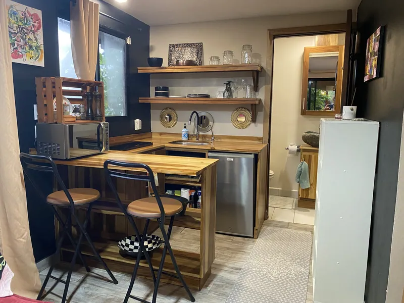 The fully equipped kitchenette with a wood counter, sink, mini-fridge, microwave, and two bar stools.