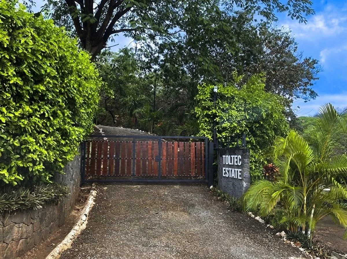 The Toltec Estate gate — wooden entry gate and stone pillar at the driveway