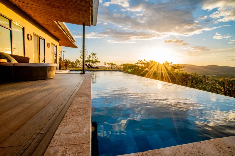 The infinity pool catching golden light, the deck running along the villa